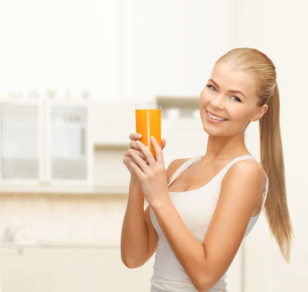 Mulher sorridente segurando vidro de suco de laranja — Fotografia de Stock