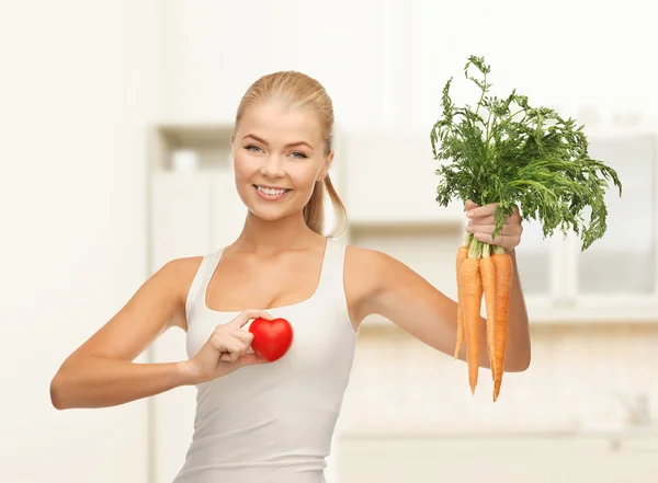Mujer sosteniendo símbolo del corazón y zanahorias — Foto de Stock