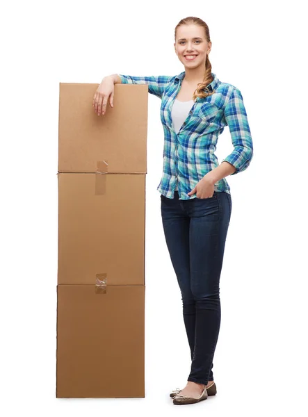 Mujer joven de pie junto a la torre de cajas — Foto de Stock