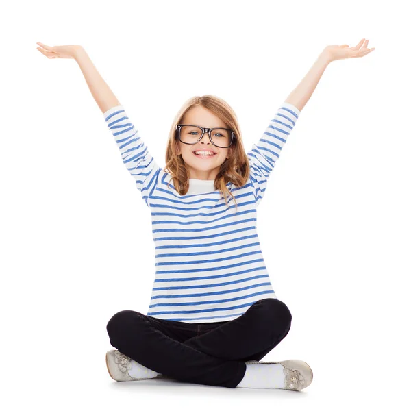 Smiling girl in eyeglasses sitting on floor — Stock Photo, Image