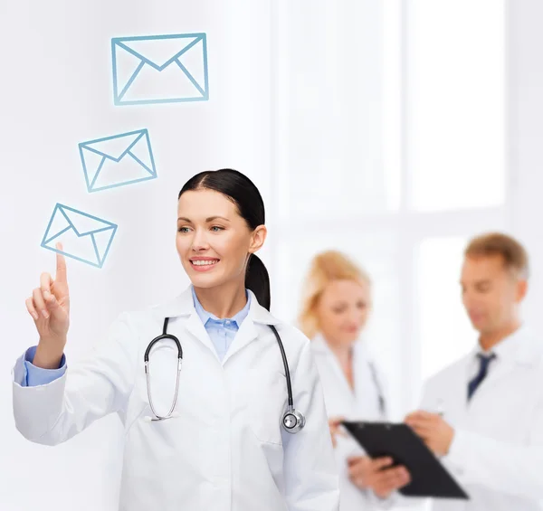 Médica sorridente apontando para envelope — Fotografia de Stock