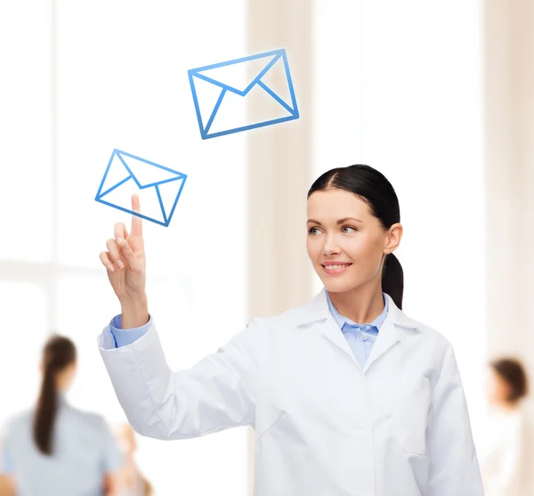 Smiling female doctor pointing to envelope — Stock Photo, Image