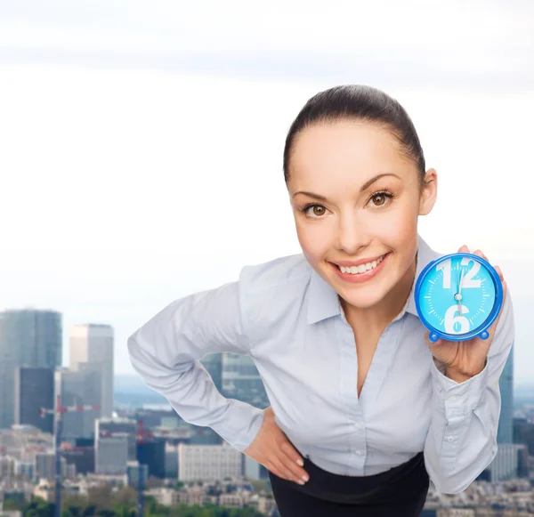 Femme d'affaires souriante avec horloge bleue — Photo