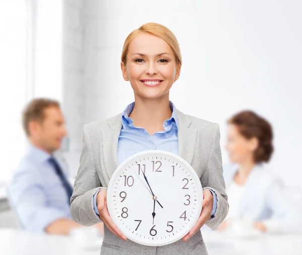 Femme d'affaires souriante avec horloge murale — Photo