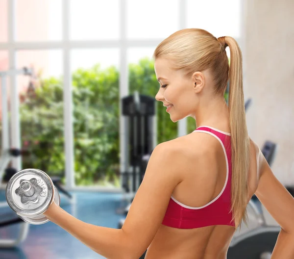 Mujer sonriente con mancuerna de acero pesado en el gimnasio — Foto de Stock