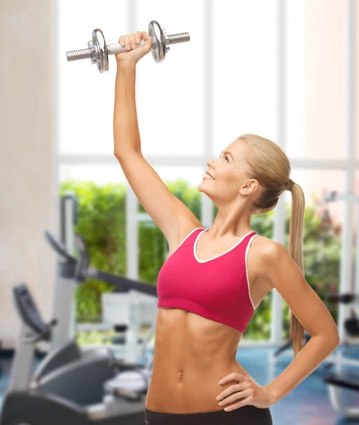 Smiling woman lifting steel dumbbell at gym — Stock Photo, Image