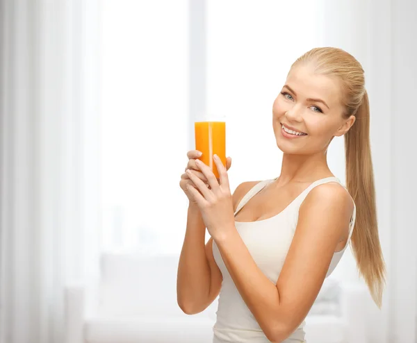 Mujer sonriente sosteniendo un vaso de jugo de naranja — Foto de Stock