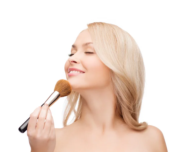 Mooie vrouw met gesloten ogen en make-up borstel — Stockfoto