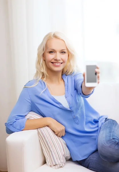 Lachende vrouw met lege smartphone scherm thuis — Stockfoto