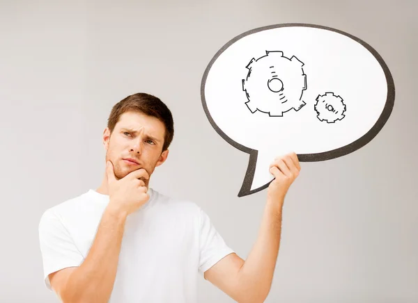 Young man with cogwheel in text bubble — Stock Photo, Image