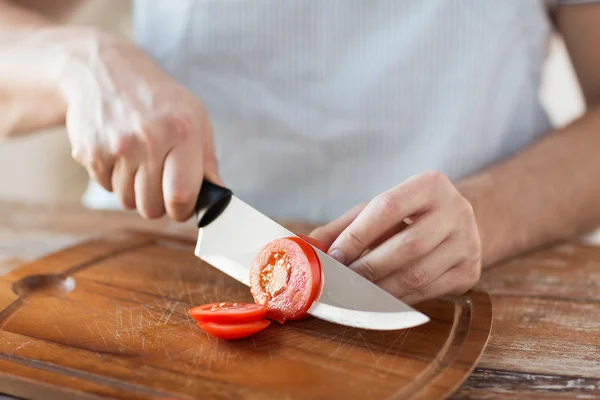 Male hand cutting tomato on board with knife — Stock Photo, Image