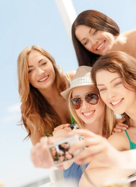 Lachende meisjes nemen van foto in café op het strand — Stockfoto