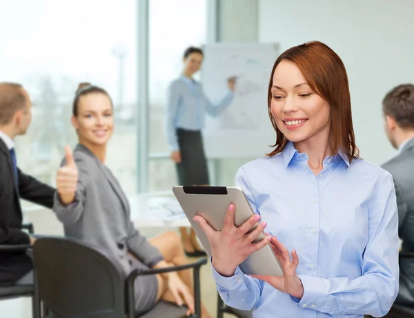 Lachende vrouw kijken naar tablet pc op kantoor — Stockfoto