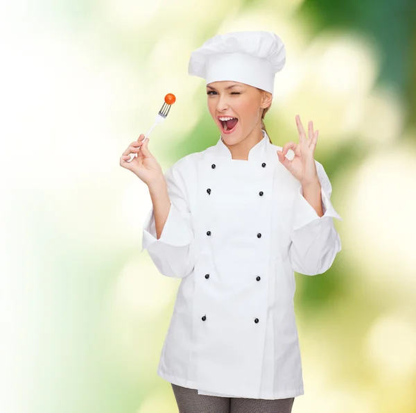 Çatal ve domates ile gülümseyen kadın aşçı — Stok fotoğraf