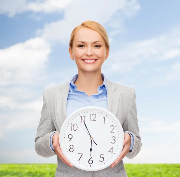 Smiling businesswoman with wall clock — Stock Photo, Image