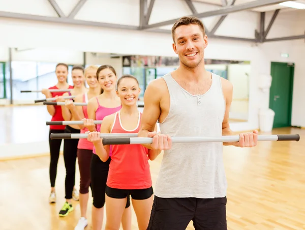 Grupo de personas sonrientes haciendo ejercicio con las barras — Foto de Stock