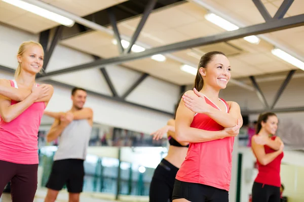 Groep glimlachende mensen die zich uitstrekt in de sportschool — Stockfoto