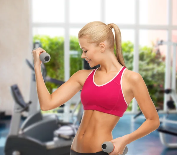 Joven mujer deportiva con pesas ligeras en el gimnasio — Foto de Stock