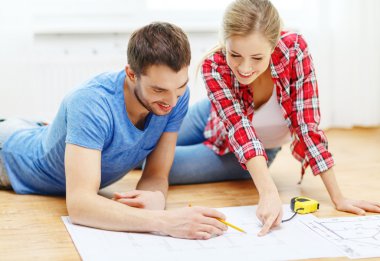 Smiling couple looking at blueprint at home clipart
