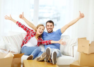 Smiling couple relaxing on sofa in new home clipart