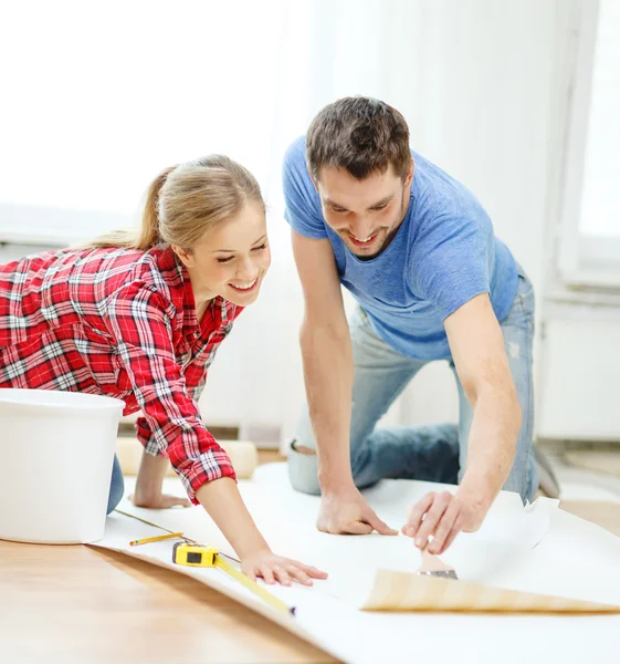 Casal sorrindo papel de parede manchando com cola — Fotografia de Stock