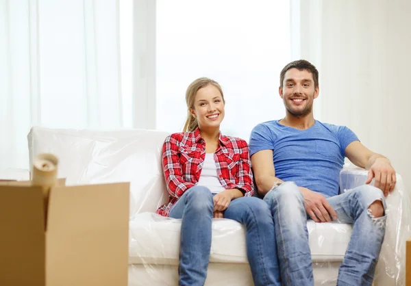 Усміхнена пара розслабляється на дивані в новому будинку — стокове фото