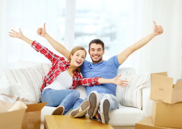 Casal sorridente relaxante no sofá em nova casa — Fotografia de Stock