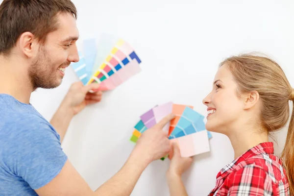 Coppia sorridente che guarda i campioni di colore a casa — Foto Stock