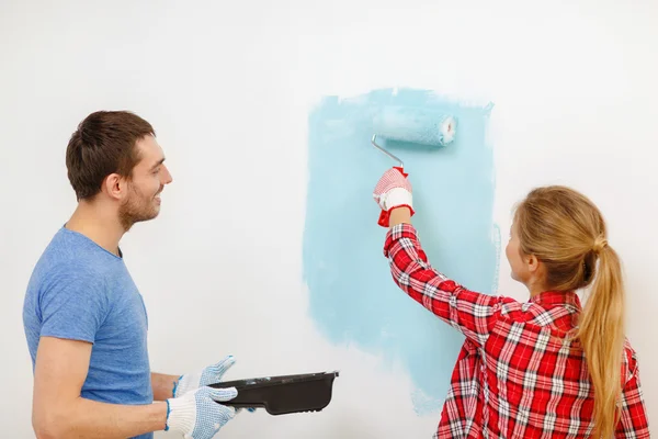 Sorrindo parede casal pintura em casa — Fotografia de Stock