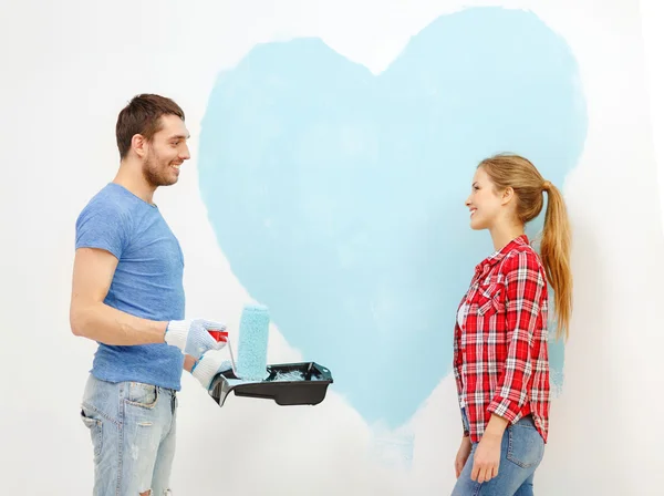 Улыбающаяся пара рисует большое сердце на стене — стоковое фото