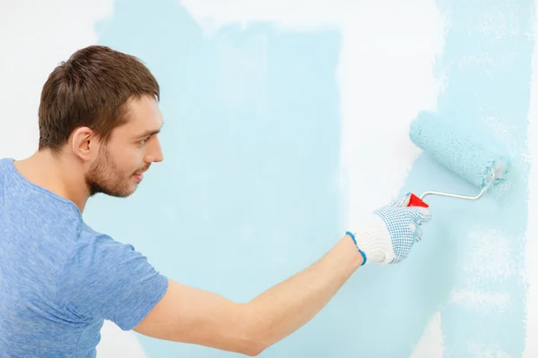 Uomo sorridente pittura muro a casa — Foto Stock