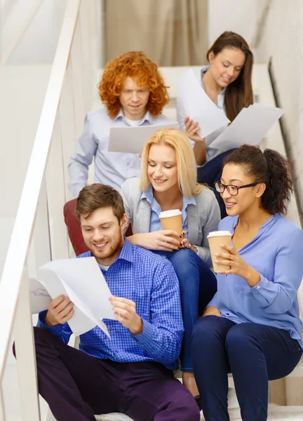 Team with papers and take away coffee on staircase — Stock Photo, Image