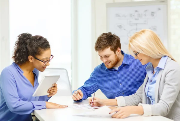 Équipe souriante avec table pc et papiers de travail — Photo