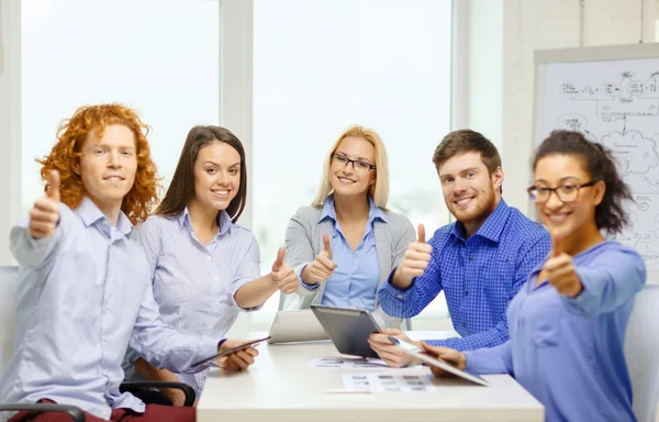 Équipe souriante avec table pc et papiers de travail — Photo