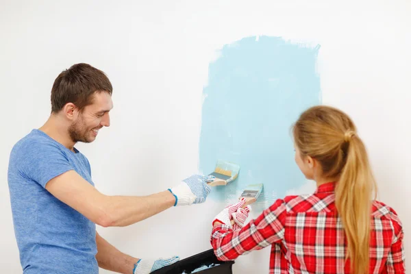 Couple souriant mur de peinture à la maison Images De Stock Libres De Droits