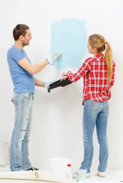 Couple souriant mur de peinture à la maison Photo De Stock