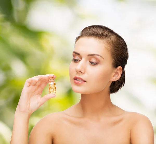 Beautiful woman showing bottle with golden dust — Stock Photo, Image