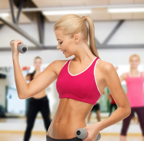 Giovane donna sportiva con manubri leggeri in palestra — Foto Stock