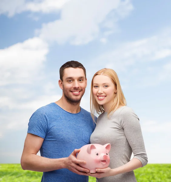 Sorrindo casal segurando grande porquinho banco — Fotografia de Stock