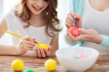 Close up of little girl and mother coloring eggs clipart