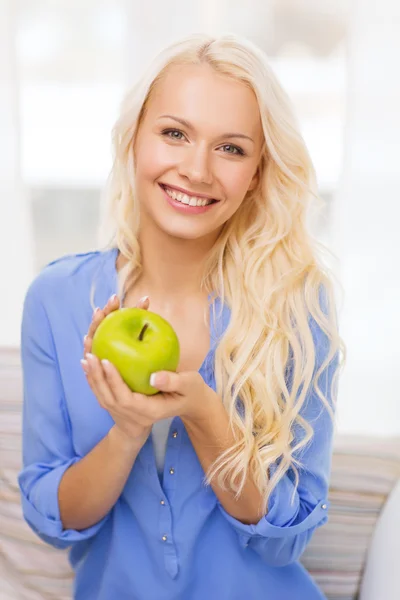 Mulher sorridente com maçã verde em casa — Fotografia de Stock