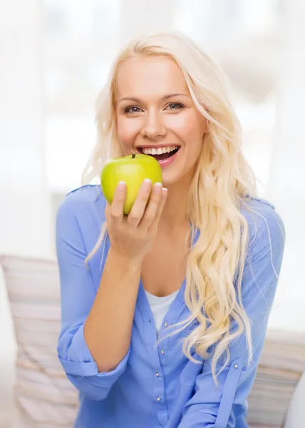 Leende kvinna med grönt äpple hemma — Stockfoto