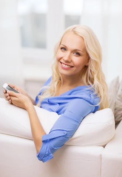 Mujer sonriente con smartphone en casa —  Fotos de Stock