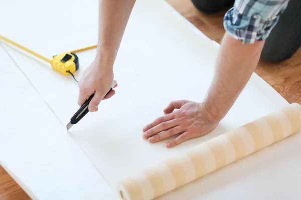 Close up van mannelijke handen snijden wallpaper — Stockfoto