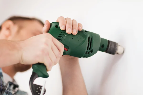 Man with electric drill making hole in wall — Stock Photo, Image