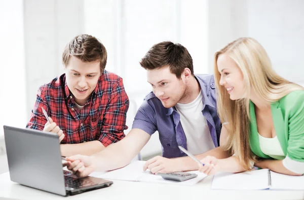 Smiling students looking at laptop at school — Stock Photo, Image