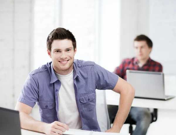 Lachende student met laptop op school — Stockfoto