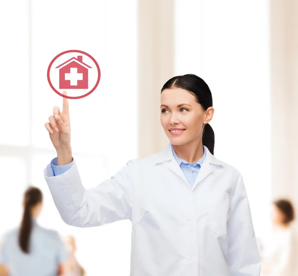 Una doctora sonriente señalando el signo del hospital —  Fotos de Stock