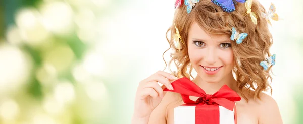 Teenager with butterflies in hair opening present — Stock Photo, Image