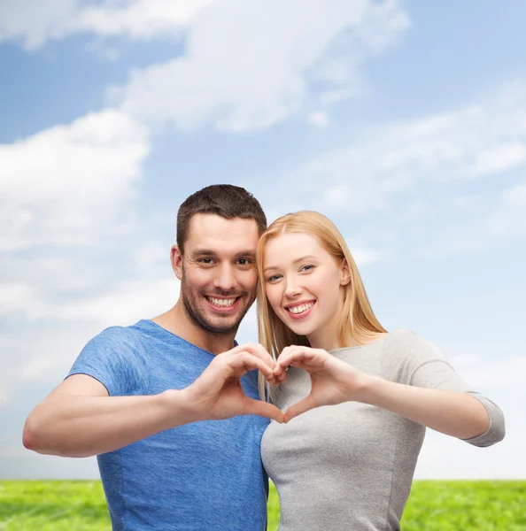 Smiling couple showing heart with hands — Stok fotoğraf